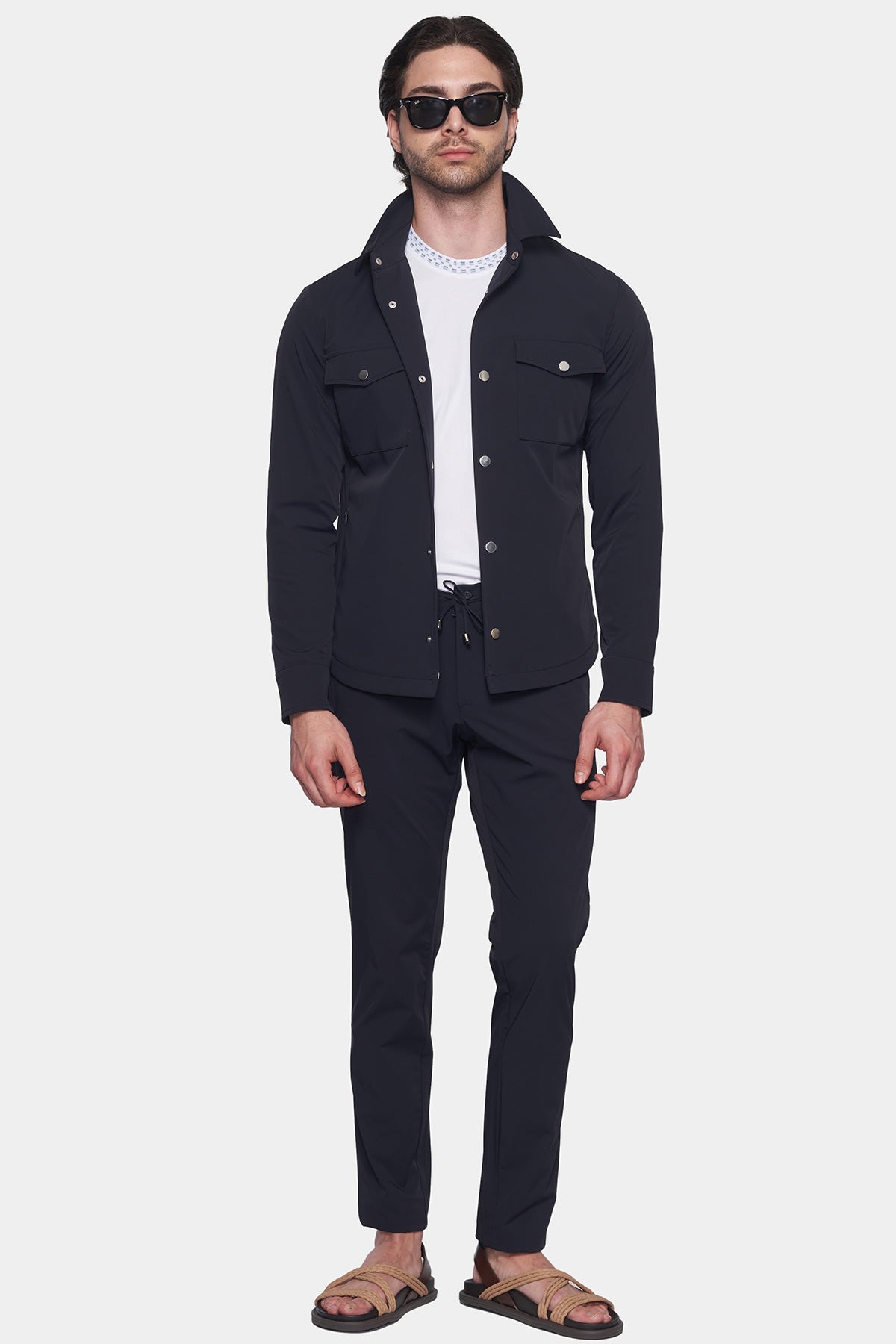 Man wearing a dark jacket and pants on a white background