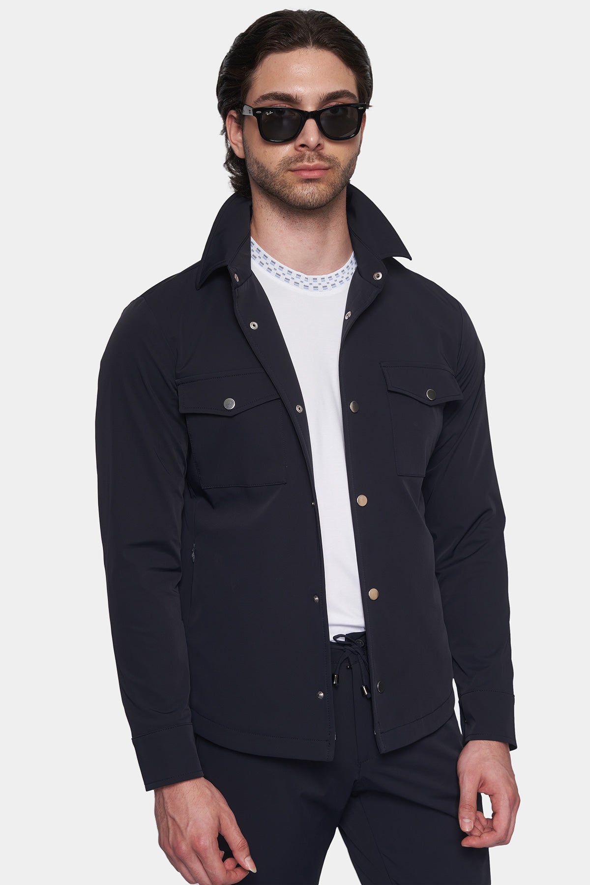 Man wearing a black jacket over a white shirt on a white background