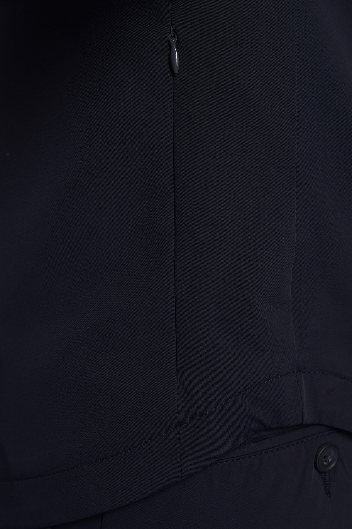 Close-up of a black jacket with a zipper and button details.
