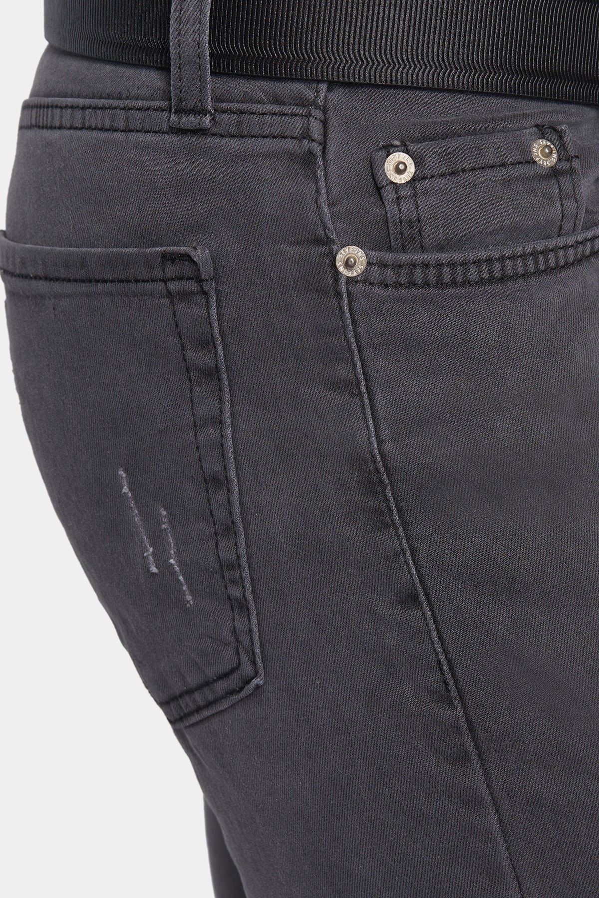 Close-up of dark gray jeans with button details on a light gray background