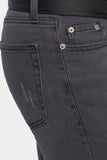 Close-up of dark gray jeans with button details on a light gray background