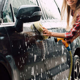 Person washing a car with a sponge and water hose