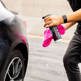 Person cleaning a car with a spray bottle and pink towel