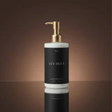 Bottle of 'Les Deux' with a gold pump on a reflective surface and brown background