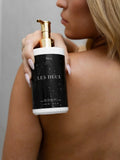 Person holding a 'Les Deux' product with a gold pump against a neutral background
