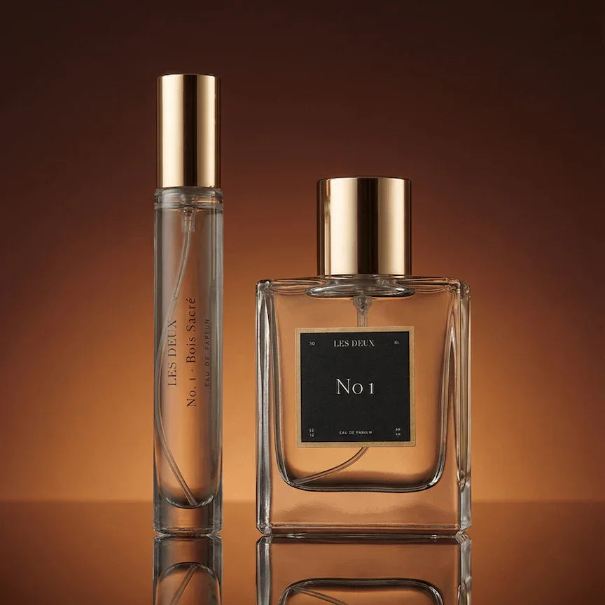 Two perfume bottles with gold caps on a brown background