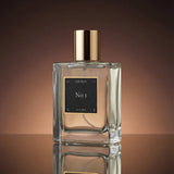 Perfume bottle with gold cap and black label on a reflective surface with a brown gradient background