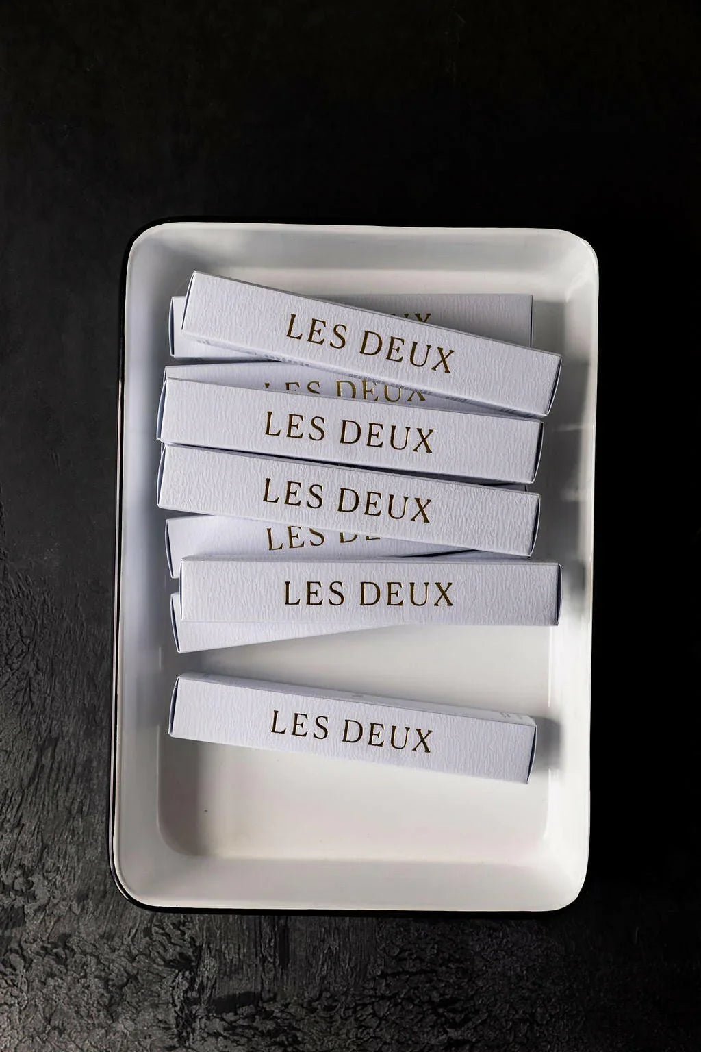 White rectangular dish with 'LES DEUX' branded items on a dark background
