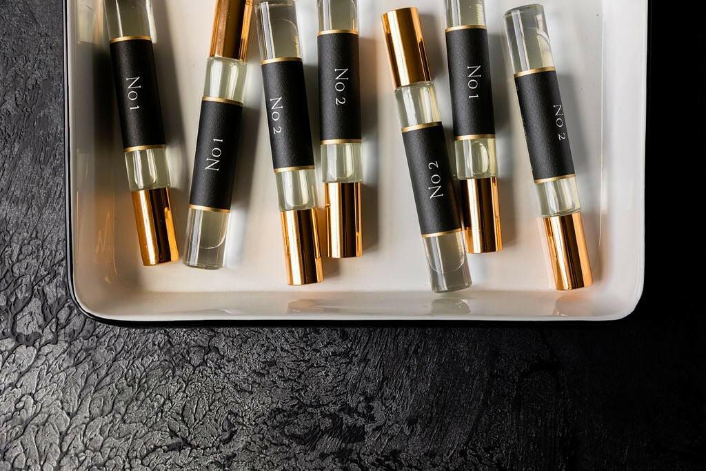 Set of perfume bottles with black labels on a white tray against a dark textured background