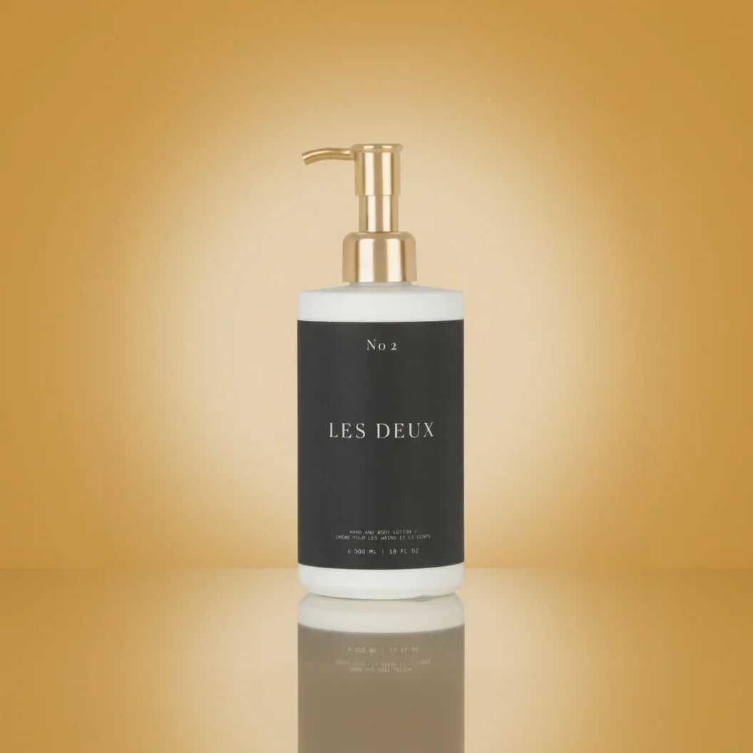 White bottle with gold pump labeled 'LES DEUX' on a gradient gold background