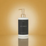 White bottle with gold pump labeled 'LES DEUX' on a gradient gold background