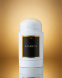 White deodorant stick with 'Les Deux' branding on a gold gradient background