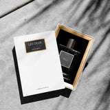 Perfume bottle and packaging with 'Les Deux' branding on a gray surface