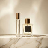 Two perfume bottles on a marble surface with a neutral background
