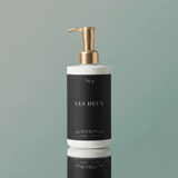 White soap dispenser with gold pump on a gray background