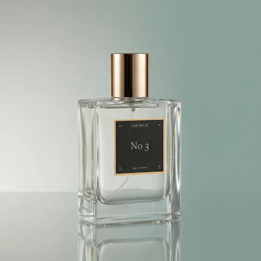Perfume bottle labeled 'No 3' with a gold cap on a reflective surface.