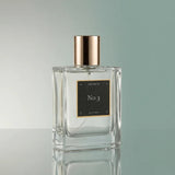 Perfume bottle labeled 'No 3' with a gold cap on a reflective surface.