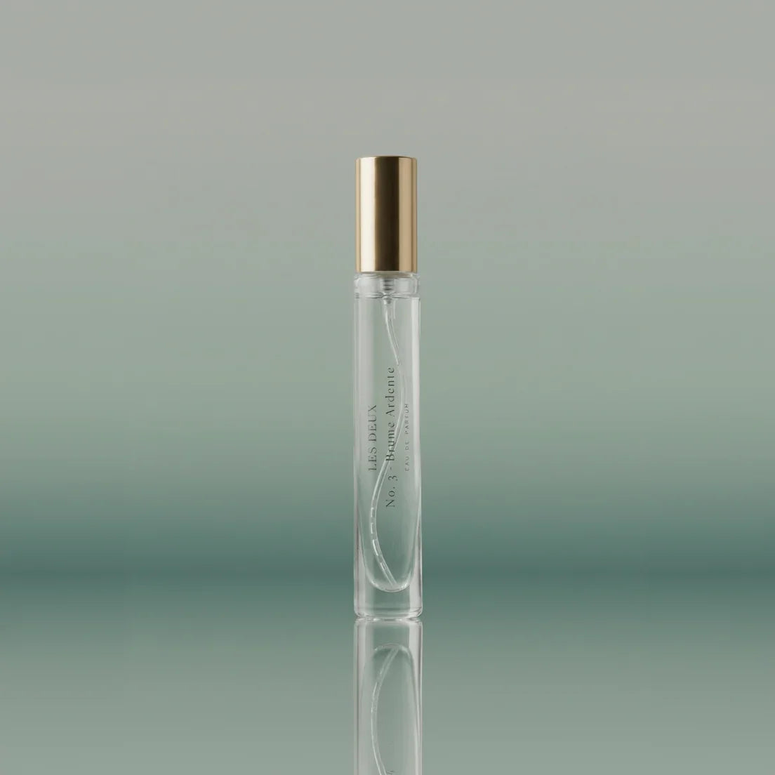 Clear perfume bottle with gold cap on a gradient green background