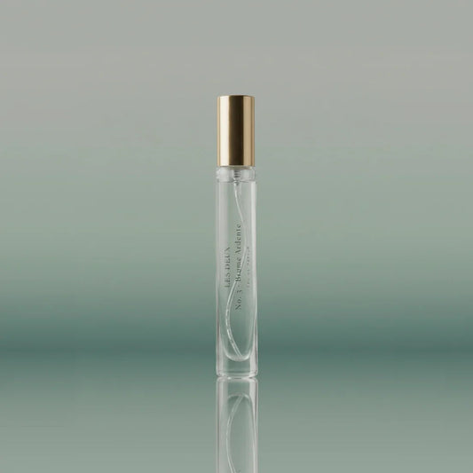 Clear perfume bottle with gold cap on a gradient green background