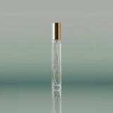 Clear perfume bottle with gold cap on a gradient green background
