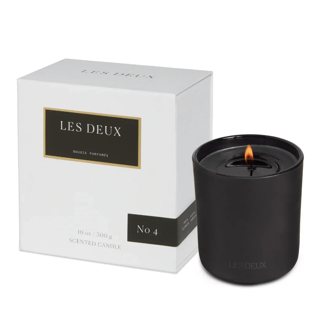 Black candle with 'LES DEUX' branding next to its packaging on a white background