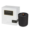 Black candle with 'LES DEUX' branding next to its packaging on a white background