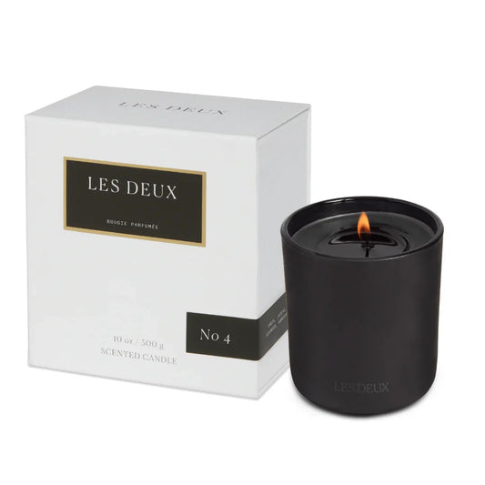 Black candle with 'LES DEUX' branding next to its packaging on a white background