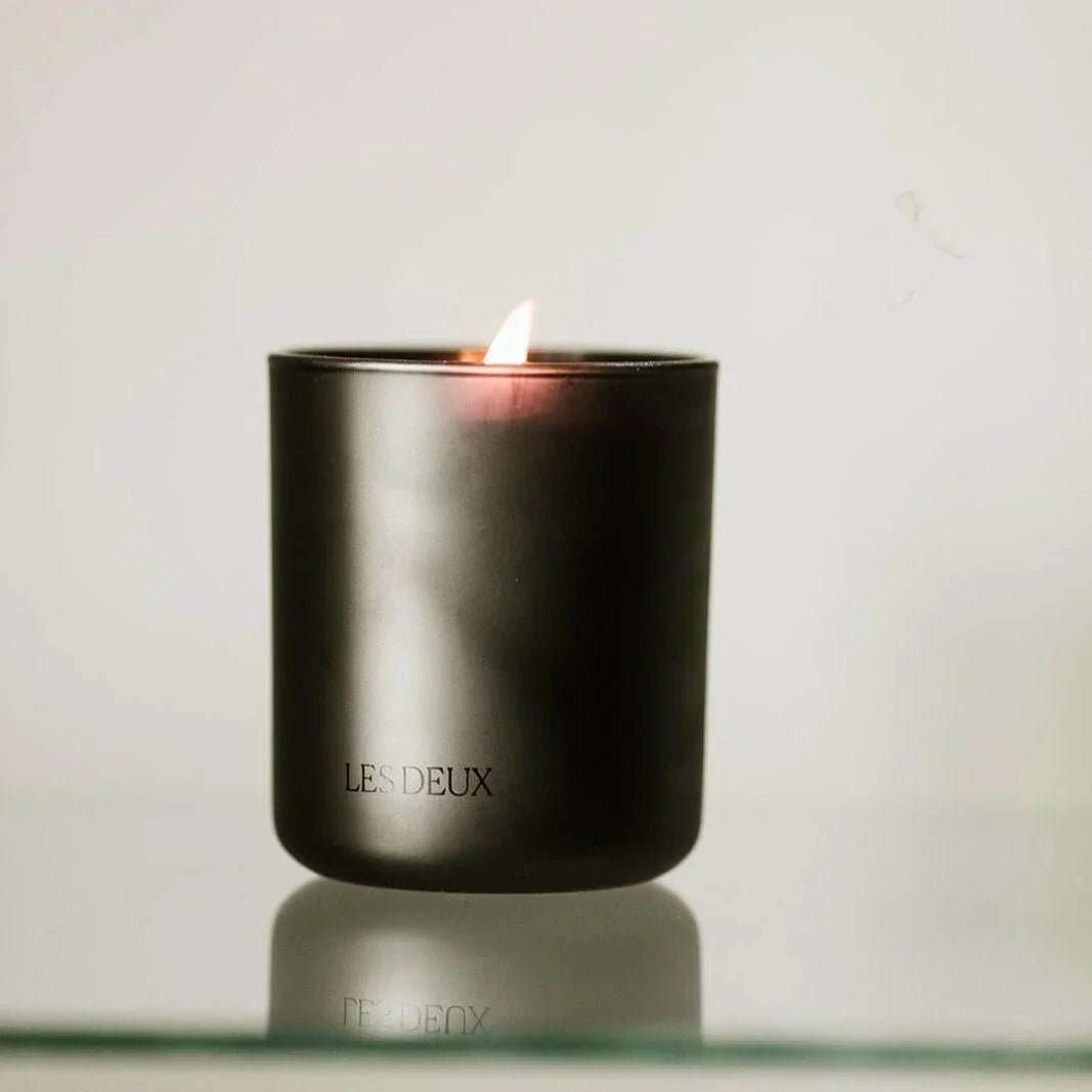 Black candle in a container with 'LES DEUX' branding on a light gray background