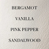 Text listing Bergamot, Vanilla, Pink Pepper, and Sandalwood on a textured beige background