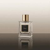 Perfume bottle labeled 'No. 4' with gold cap on a reflective surface.