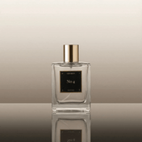 Perfume bottle labeled 'No. 4' by 'Les Deux' on a reflective surface with a neutral background