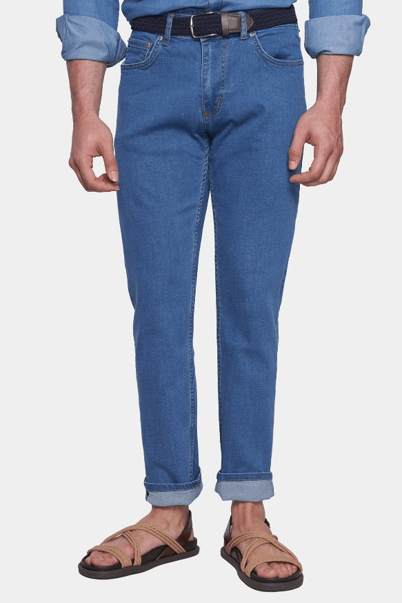 Person wearing blue jeans and brown sandals on a white background