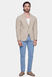 Man wearing a beige blazer, white shirt, and blue jeans on a white background