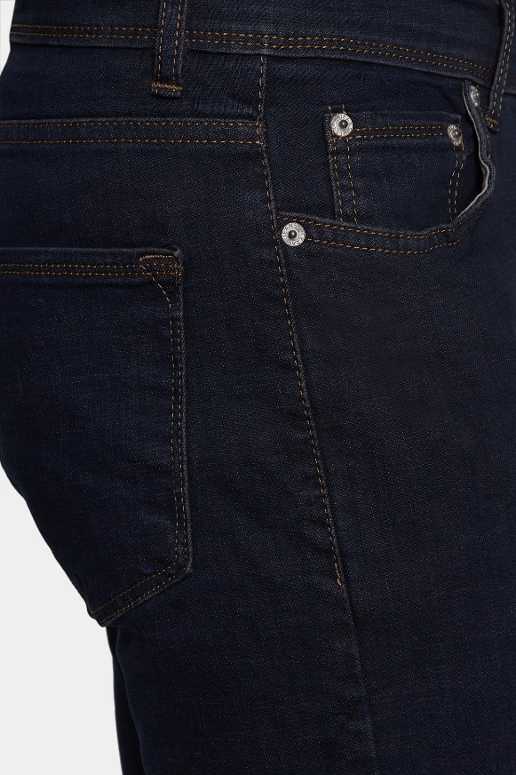 Close-up of dark blue jeans with stitching details on a white background