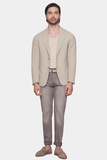 Man wearing a beige blazer, beige shirt, and gray pants on a white background