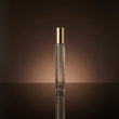 Perfume bottle with gold cap on a reflective surface and brown background