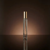 Perfume bottle with gold cap on a reflective surface and brown background
