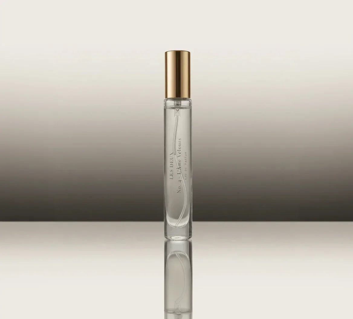 Clear perfume bottle with gold cap on a reflective surface and gradient background