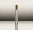 Clear perfume bottle with gold cap on a reflective surface and gradient background
