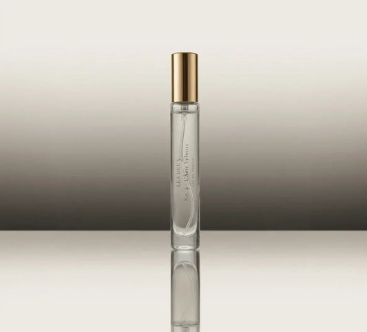 Clear perfume bottle with gold cap on a reflective surface and gradient background