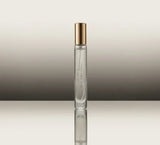 Clear perfume bottle with gold cap on a reflective surface and gradient background